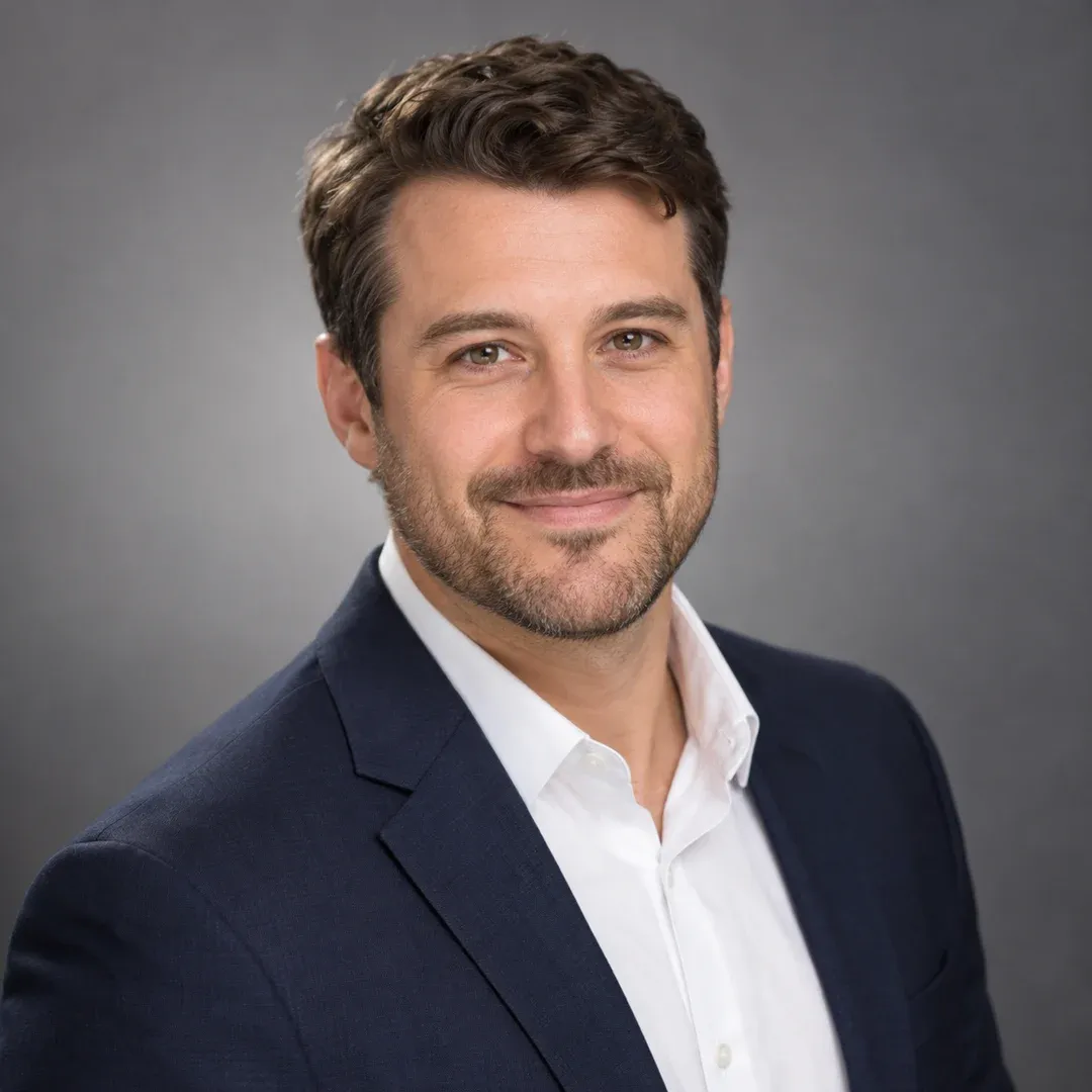 Example result: A professional head-and-shoulders headshot in a navy blazer against a soft grey studio backdrop.