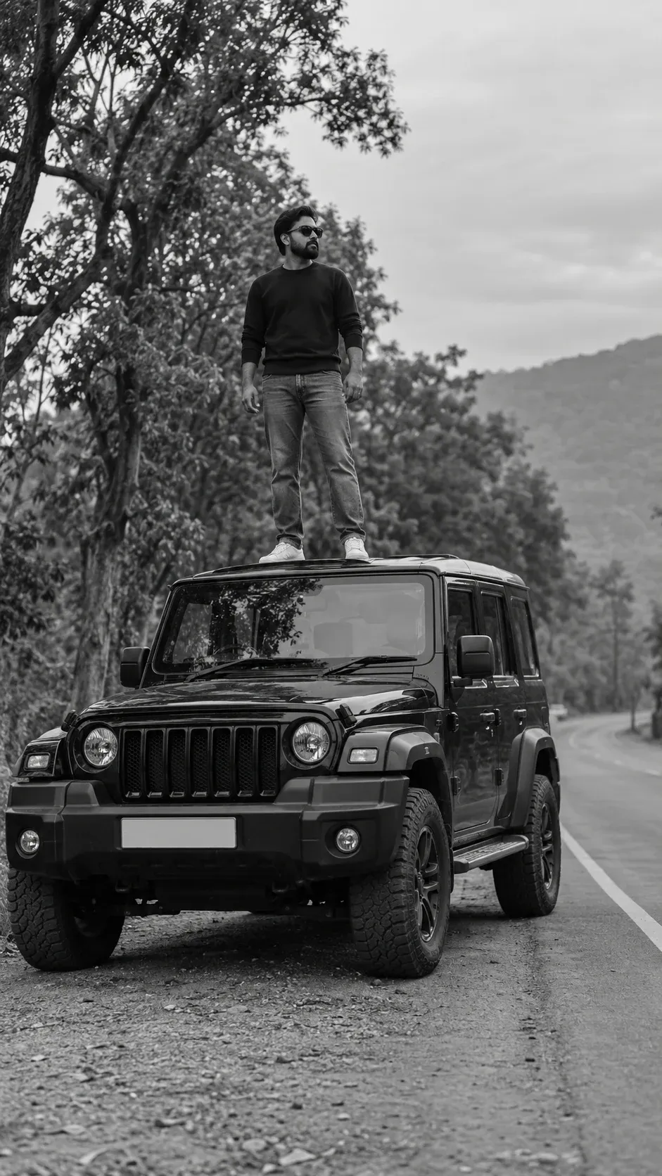 Example result: A young man in sunglasses stands on the roof of a black off-road SUV parked by a tree-lined road, in black and white.